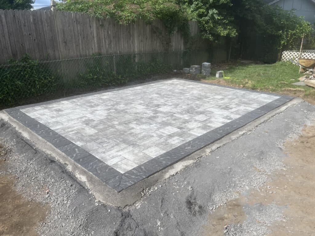 Backyard paver patio installation with dark border edging and hardscaping design
