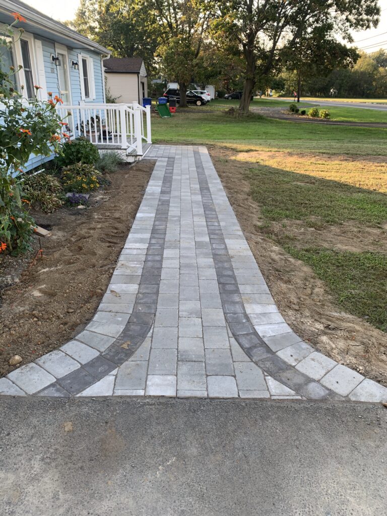 New paver walkway installation in front of blue house hardscaping project