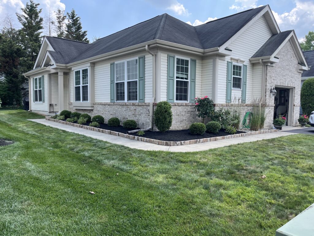 Brick ranch home front yard after mulch installation with boxwood ball plantings
