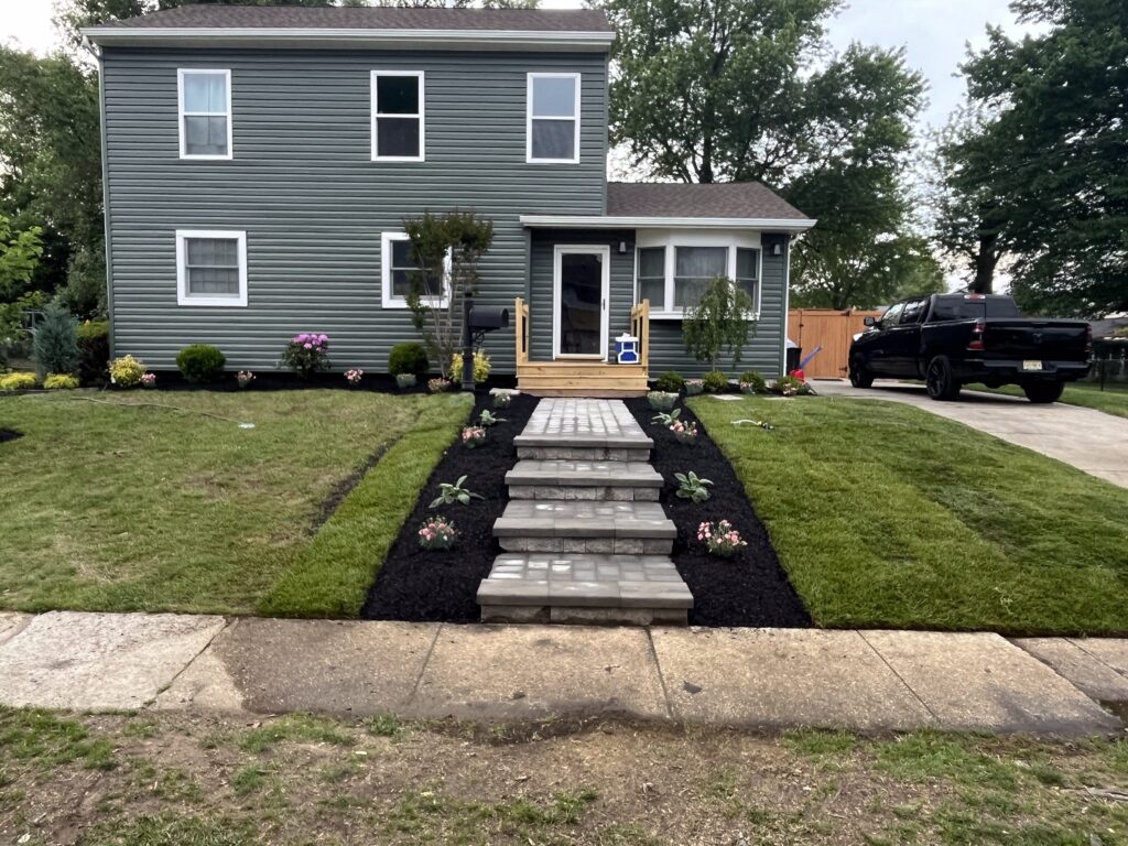 Front paver walkway and steps installation with new plantings on gray house
